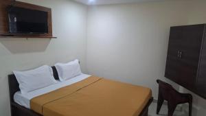 a small bedroom with a bed and a television at JJ Comfort Hotel in Turuvekere