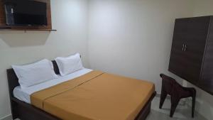 a small bedroom with a bed and a chair at JJ Comfort Hotel in Turuvekere