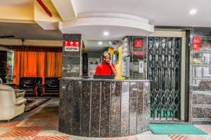 a man standing behind a counter in a lobby at Super Hotel O Src Grand in Vijayawāda +23 photos