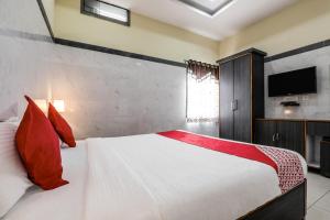 a bedroom with a large white bed with red pillows at Super Hotel O Src Grand in Vijayawāda