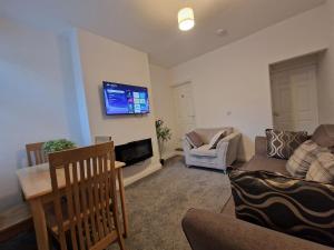 a living room with a couch and a tv on the wall at Nice Living Serviced Accommodations 14 in Coventry