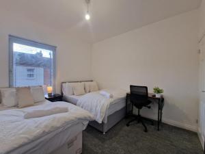 two beds in a room with a desk and a chair at Nice Living Serviced Accommodations 14 in Coventry +8 photos