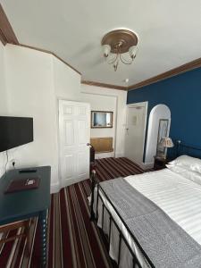 a hotel room with a bed and a tv and a door at Morlea Guest House in Llandudno