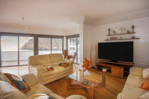 a living room with two couches and a flat screen tv at Beachfront Penthouse with Panoramic Ocean-View Terrace VIP Baia in Machico