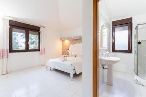 a white bathroom with a bed and a sink at Charme in Solèminis