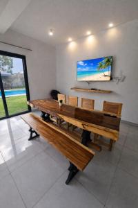 a dining room with a bench and a flat screen tv at Ivy Villa Cabarete, fully equipped villa in Cabarete