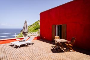 a deck with chairs and a table and an umbrella at Faro di Punta Fenaio - Caletta Privata in Campese