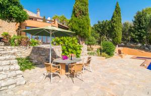 a table and chairs with an umbrella on a patio at S'alzinar Gran in Artá