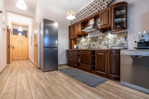 a kitchen with wooden cabinets and a stainless steel refrigerator at Góralski Przystanek Jacuzzi & sauna - dom dla 17 osób in Biały Dunajec
