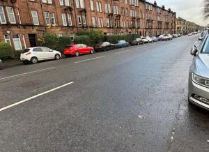 a row of cars parked on the side of a street at Stylish Glasgow Apartment in Whiteinch