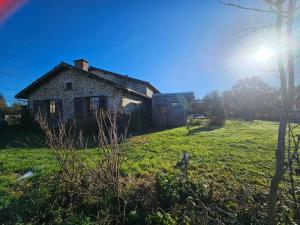 an old house on a field with the sun in the sky at Ferme écologique in Saint-Junien-les-Combes