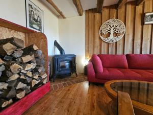 a living room with a red couch and a fireplace at Ferme écologique in Saint-Junien-les-Combes