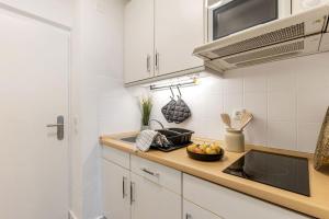 a kitchen with white cabinets and a sink with a bowl of fruit at Sea la Vie - Seitlicher Meerblick zwischen Südstrand und Yachthafen in Fehmarn