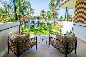a balcony with chairs and a table and palm trees at Kombo Beach Resort in Serekunda