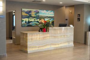 un comptoir de réception avec une peinture sur le mur dans l'établissement Encore Suites by Service Plus Inns, à Grande Prairie