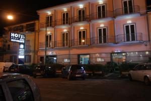 un edificio con coches aparcados delante de él por la noche en Hotel Elio en Marigliano