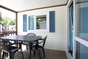 a porch with a table and chairs and a window at ZEcamping 3 étoiles chiens acceptés piscine en bord de rivière avec Canoë in Mazères