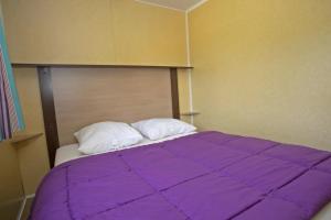 a bed with a purple comforter and two pillows at ZEcamping 3 étoiles chiens acceptés piscine en bord de rivière avec Canoë in Mazères +41 photos
