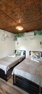 two beds in a room with a wooden ceiling at RC Hutspot Tourist Inn in San Francisco