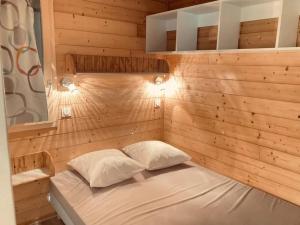 a small bed in a wooden room with two pillows at ZEcamping 3 étoiles Aveyron - Espace aquatique calme et nature in Montlaur
