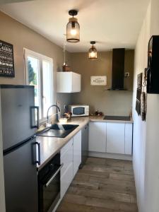 a kitchen with white cabinets and a black refrigerator at Maison côté lac in Parentis-en-Born