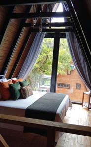 a bed in a room with a large window at Refúgio Bocaina in Bocaina do Sul
