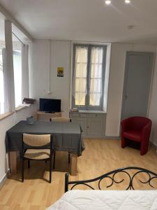 a living room with a table and a red chair at L'Abbatiale in Néris-les-Bains