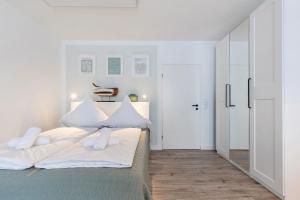 a white bedroom with a bed with white pillows at Sea la Vie - Seitlicher Meerblick zwischen Südstrand und Yachthafen in Fehmarn +12 photos