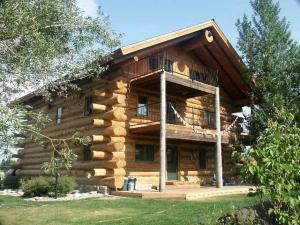 a large log cabin with a balcony on it at Spectacular Large Group Accommodations With Gallatin River Access! in Bozeman