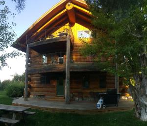 a large log cabin with a deck and a bench at Spectacular Large Group Accommodations With Gallatin River Access! in Bozeman +21 photos