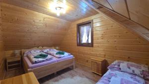 a bedroom with two beds in a log cabin at Chata vo dvore in Osturňa