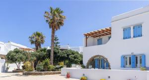 a white house with blue windows and palm trees at Home sea home in Agios Ioannis