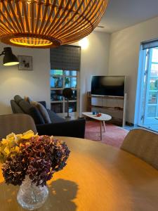 a living room with a table with a vase of flowers on it at Carlsminde ferielejlighed in Stenstrup