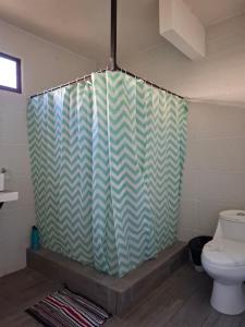 a bathroom with a shower curtain and a toilet at Coco Beach House in Coco