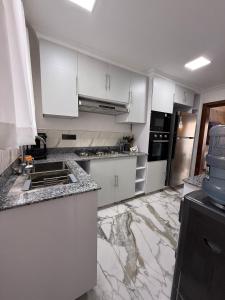 a kitchen with white cabinets and a marble floor at Sage Homes in Nairobi