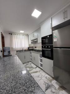 a large kitchen with white cabinets and black appliances at Sage Homes in Nairobi +1 photo
