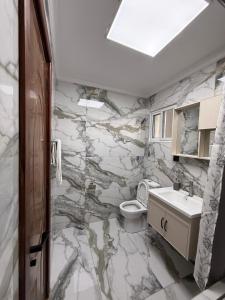 a marble bathroom with a toilet and a sink at Sage Homes in Nairobi