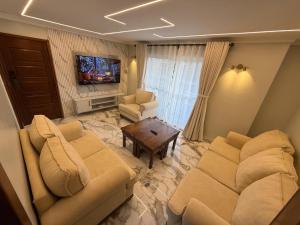 a living room with two couches and a tv at Sage Homes in Nairobi