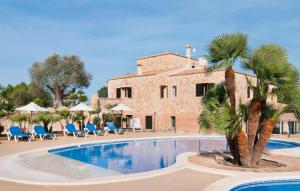 a pool with a palm tree in front of a building at Can Picafort in Can Picafort
