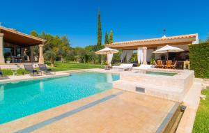 a swimming pool with chairs and umbrellas next to a house at Golf Marina in Pollença