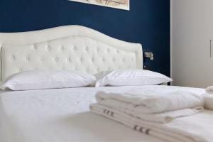a white bed with white pillows and a blue wall at IseoLakeRental - Panorama House in Parzanica +17 photos