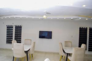 a room with two tables and chairs and a tv at Greystone Hotel in Asaba