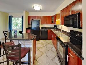 a kitchen with wooden cabinets and a black appliances at Put-in-Bay Poolview Condo #6 in Put-in-Bay