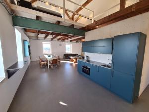 a large kitchen with blue cabinets and a table at Loft zum alten Kraftwerk in Herzogenburg +17 photos
