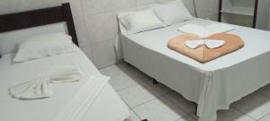 a bedroom with two beds with a heart shaped towel at Hotel Plaza Lampião in Serra Talhada