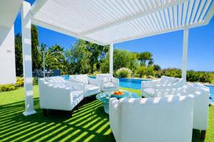 a white pergola with white chairs and a table at CASA DO LAGO, Infinity Pool, Mountains & Sea view in Estói