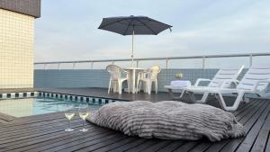 a patio with a table and chairs and an umbrella at Cobertura Duplex a Beira-Mar de Capão da Canoa in Capão da Canoa