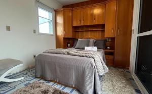 a bedroom with a large bed with wooden cabinets at Cobertura Duplex a Beira-Mar de Capão da Canoa in Capão da Canoa