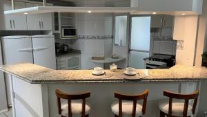 a kitchen with a counter with four chairs and a counter top at Cobertura Duplex a Beira-Mar de Capão da Canoa in Capão da Canoa