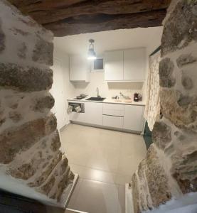 a kitchen with white cabinets and a stone wall at Agali Luxury Home in Khamilón
